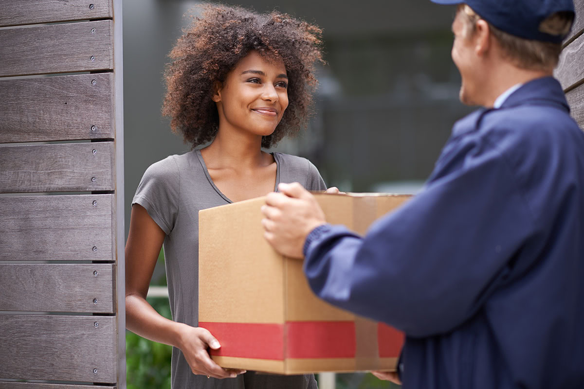 A woman holding onto a box while standing next to another man.