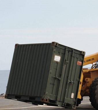 A yellow tractor pulling a green container.